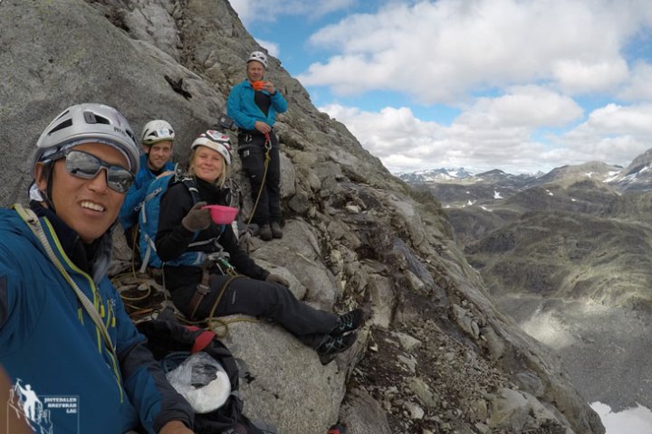 a person sitting on a rock next to a mountain