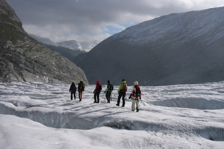 a group of people walking across the glacier